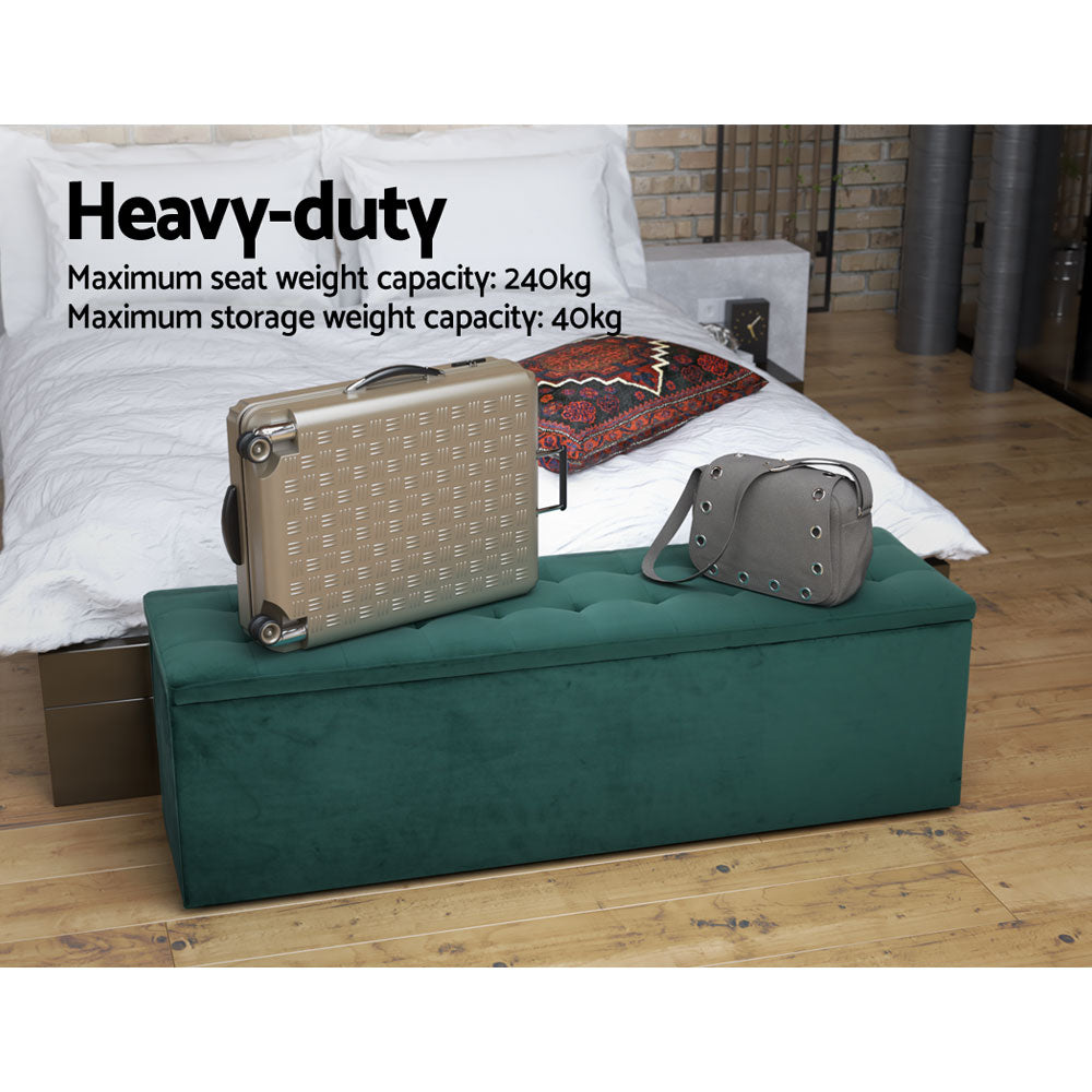 Green velvet ottoman at foot of bed providing extra seating and hidden storage